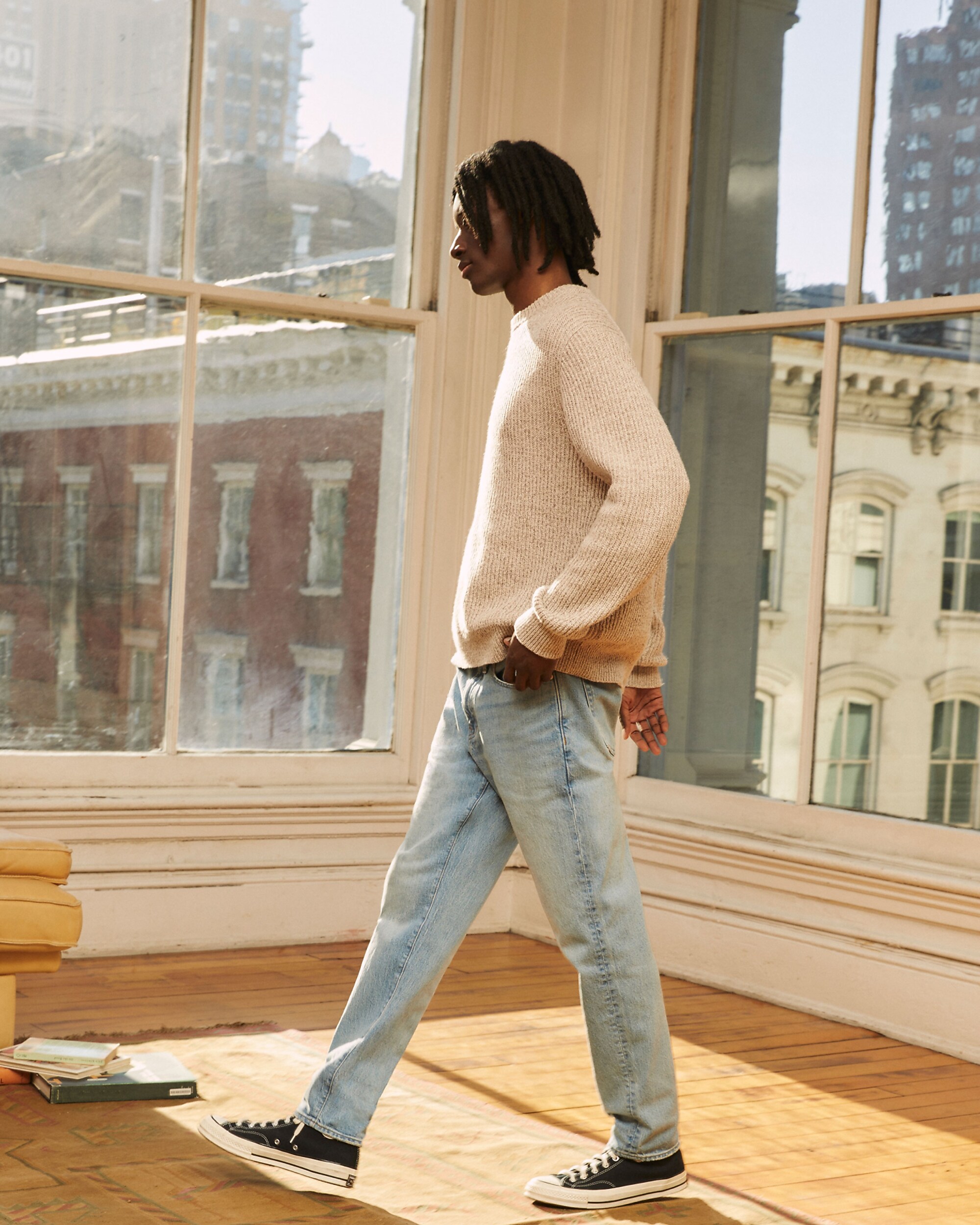 man standing in front of a parachute with classic beige shorts, white top, and a beige shirt
