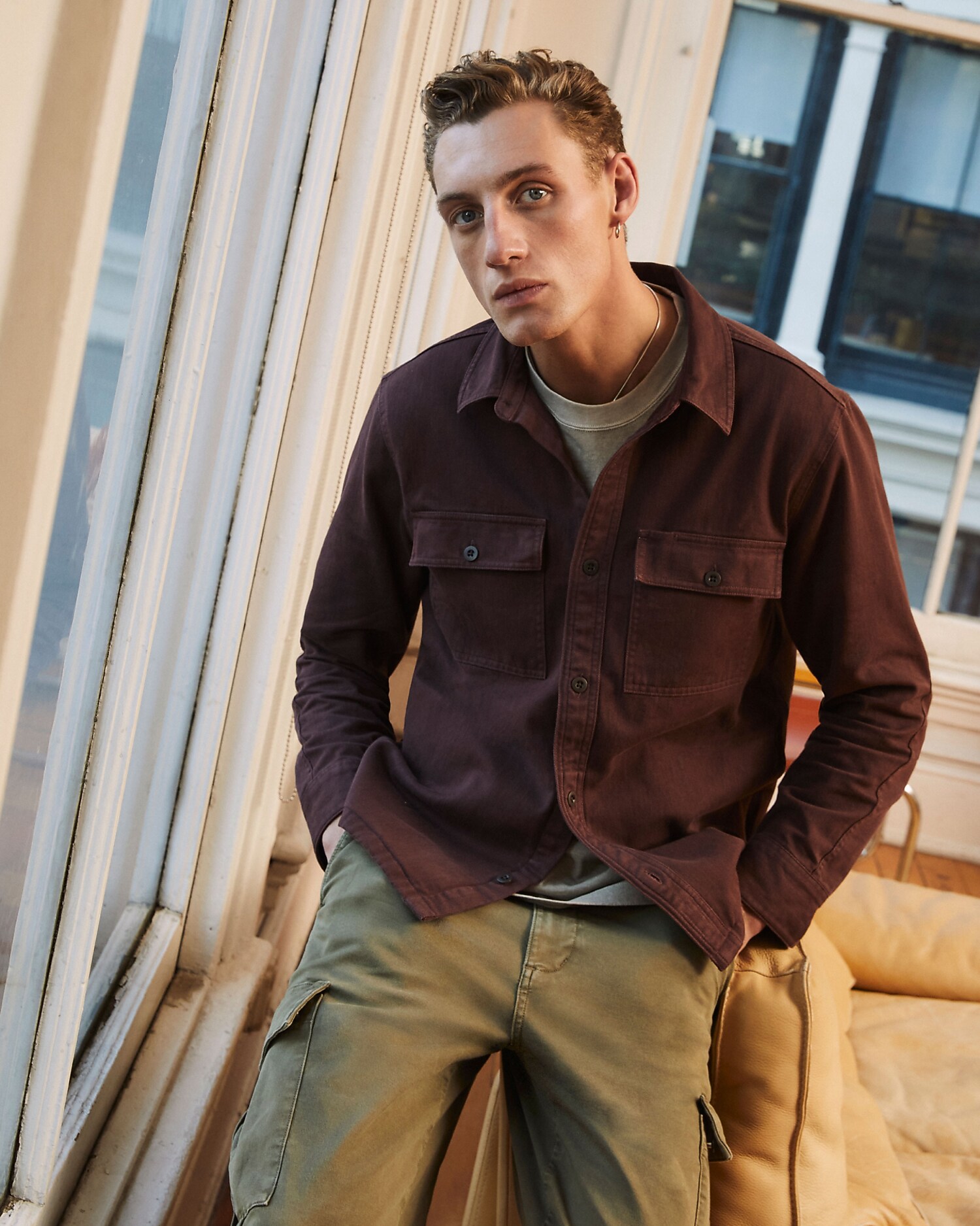 man standing in front of a parachute with classic beige shorts, white top, and a beige shirt
