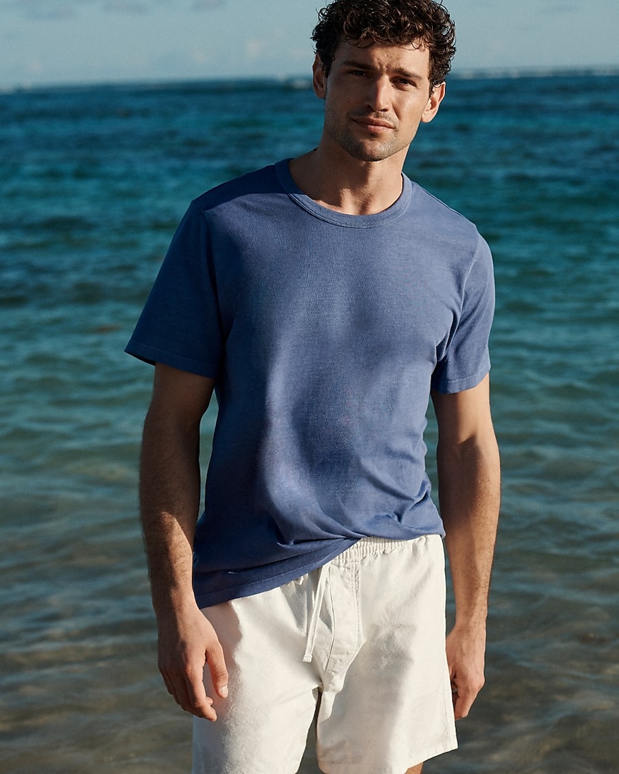 man standing in front of a parachute with classic beige shorts, white top, and a beige shirt