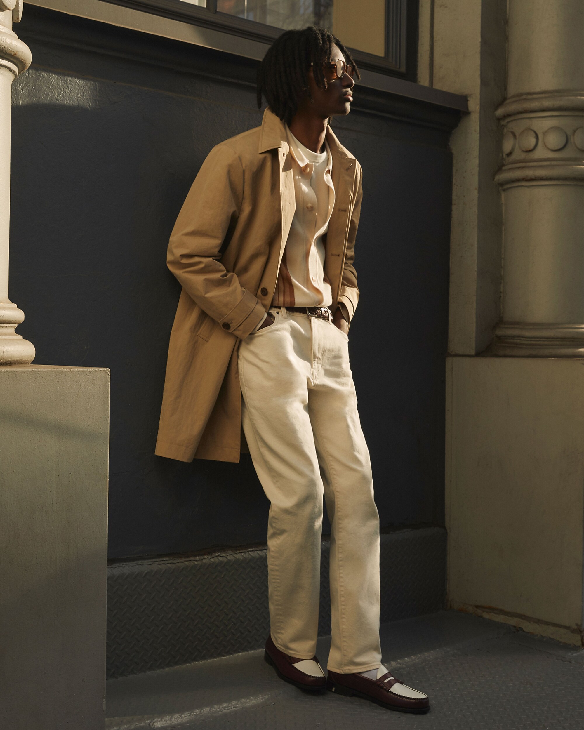 man standing in front of a parachute with classic beige shorts, white top, and a beige shirt