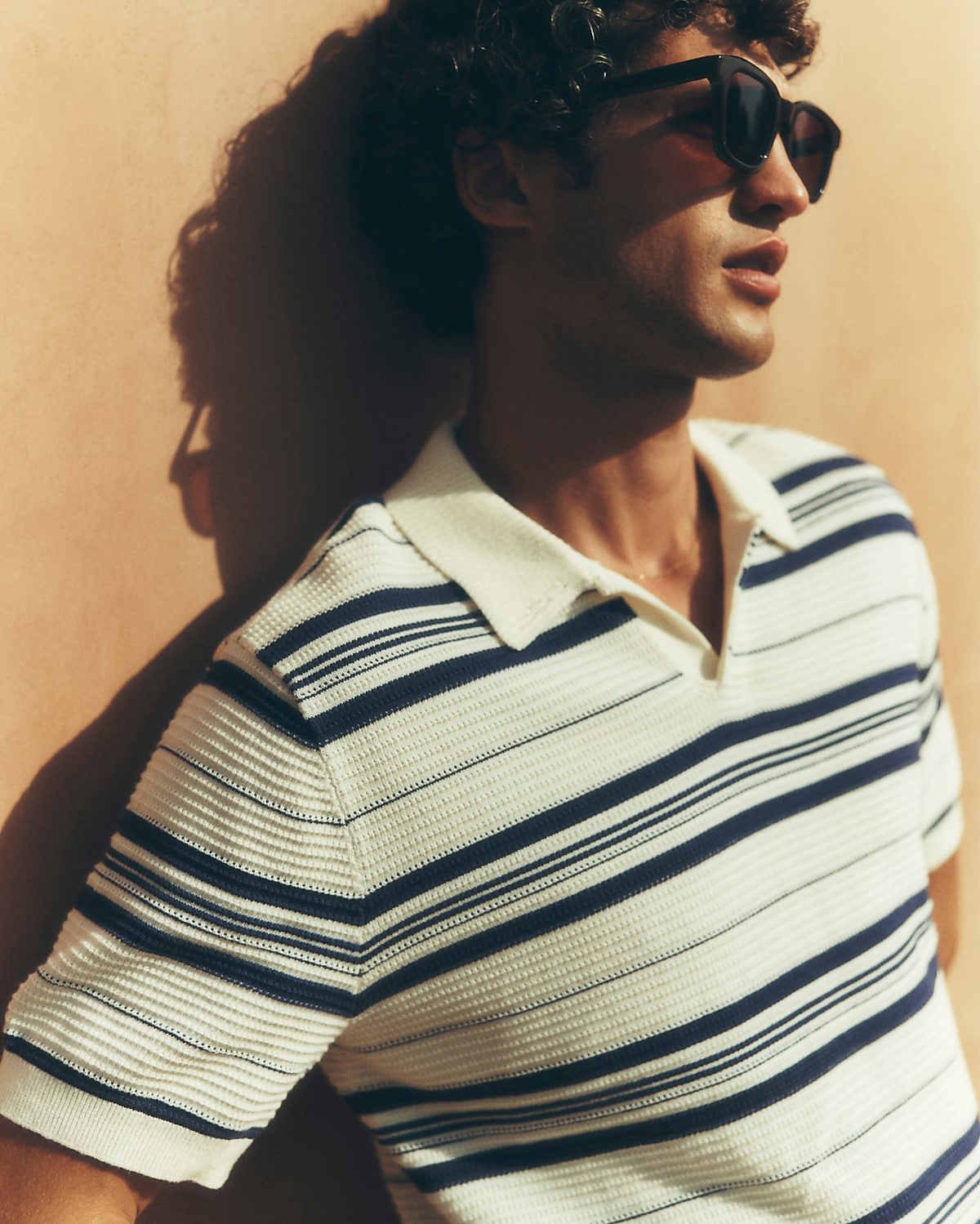 man standing in front of a parachute with classic beige shorts, white top, and a beige shirt