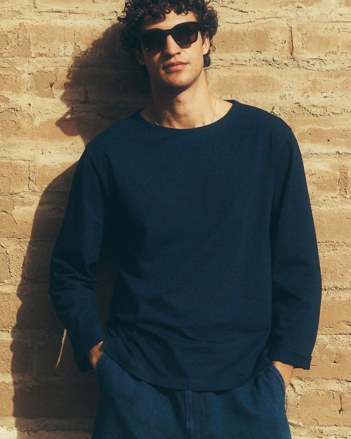 man standing in front of a parachute with classic beige shorts, white top, and a beige shirt