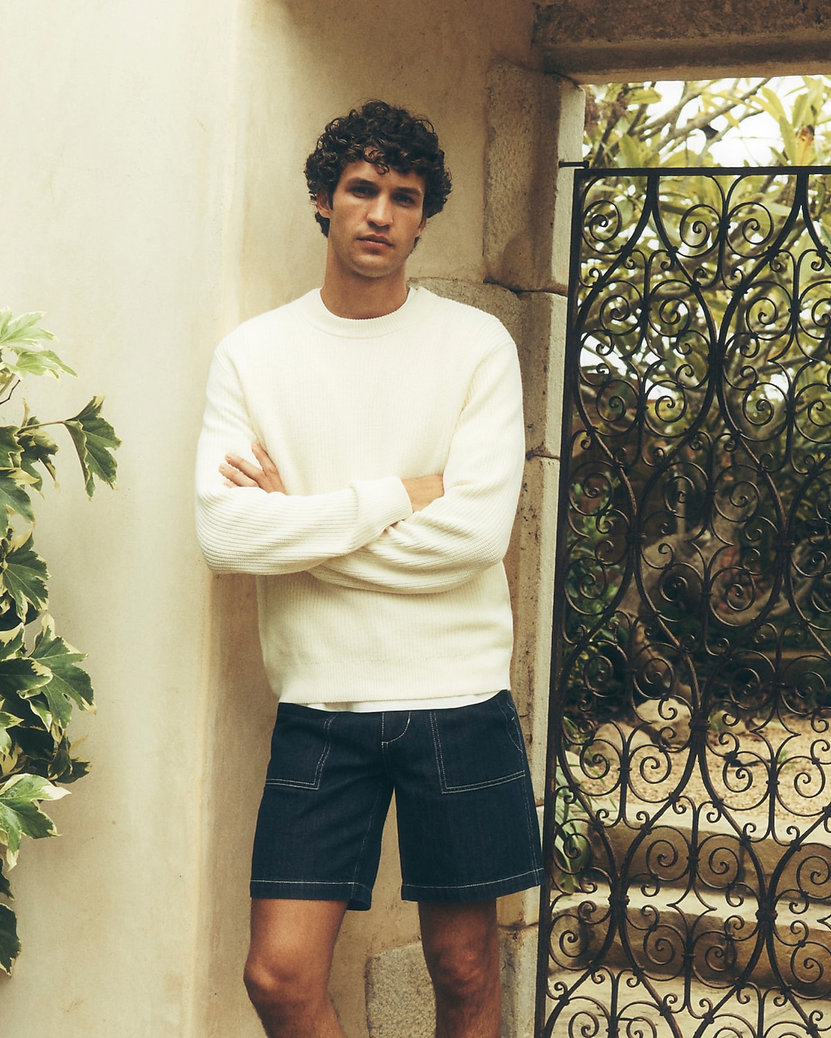 man standing in front of a parachute with classic beige shorts, white top, and a beige shirt