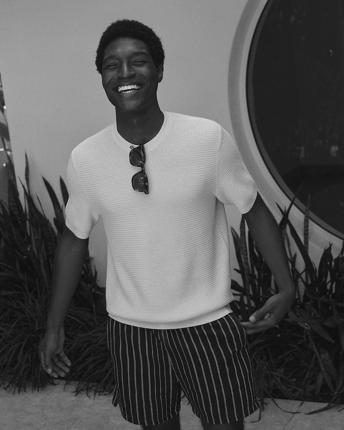 man standing in front of a parachute  with classic beige shorts, white top, and a beige shirt