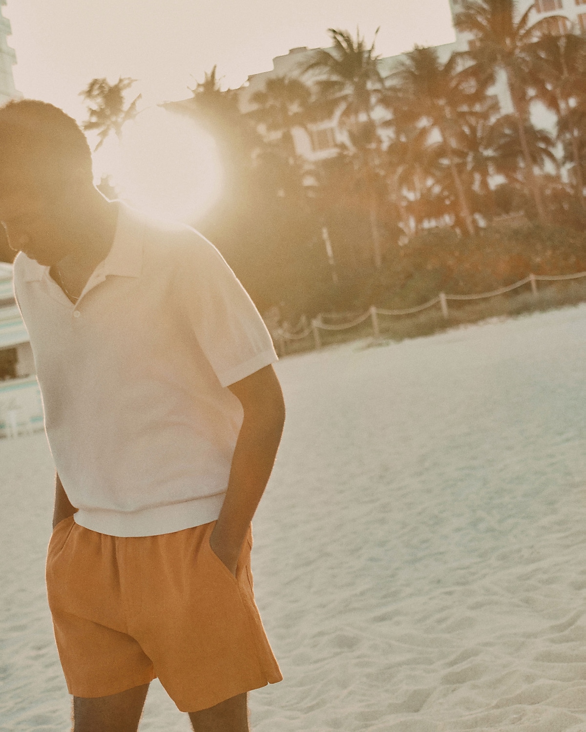 man standing in front of a parachute  with classic beige shorts, white top, and a beige shirt