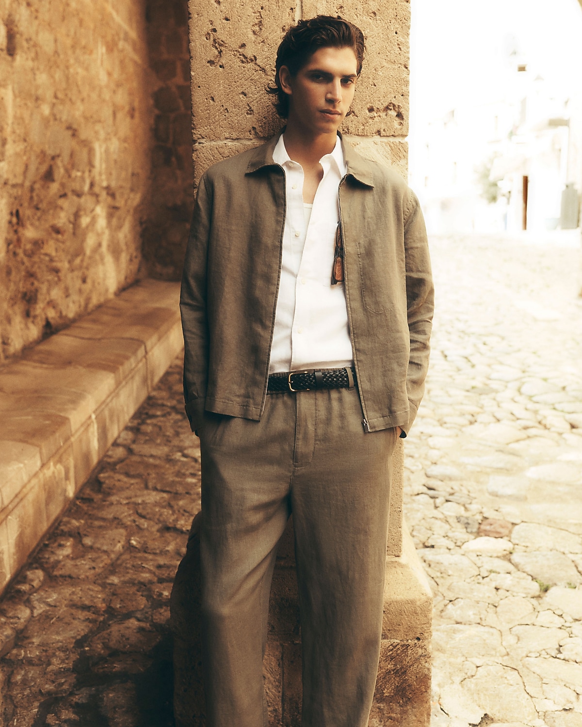 man standing in front of a parachute  with classic beige shorts, white top, and a beige shirt