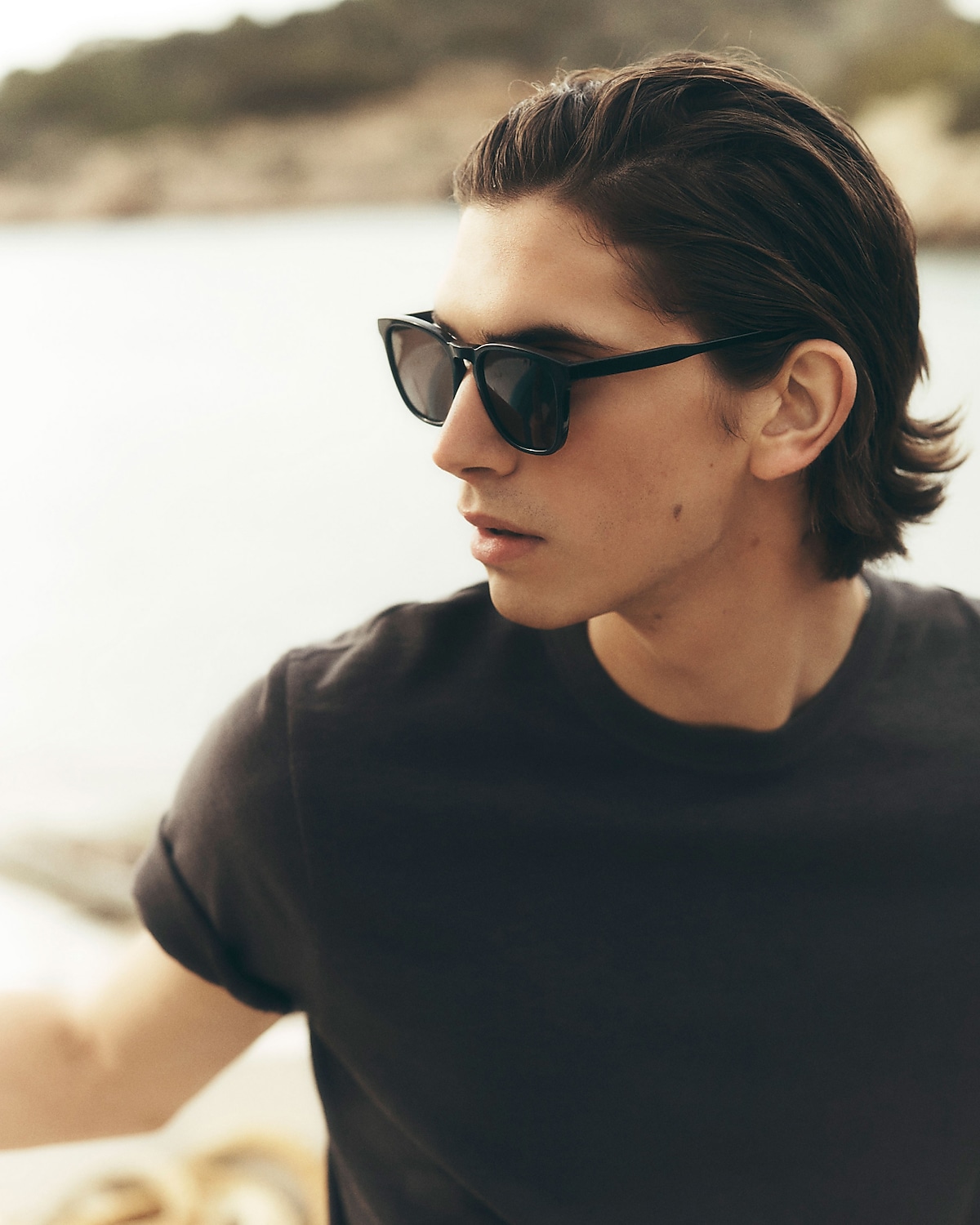 man standing in front of a parachute  with classic beige shorts, white top, and a beige shirt