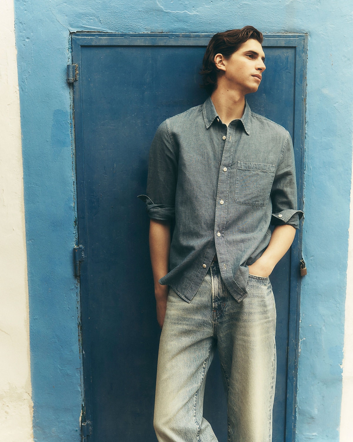 man standing in front of a parachute  with classic beige shorts, white top, and a beige shirt
