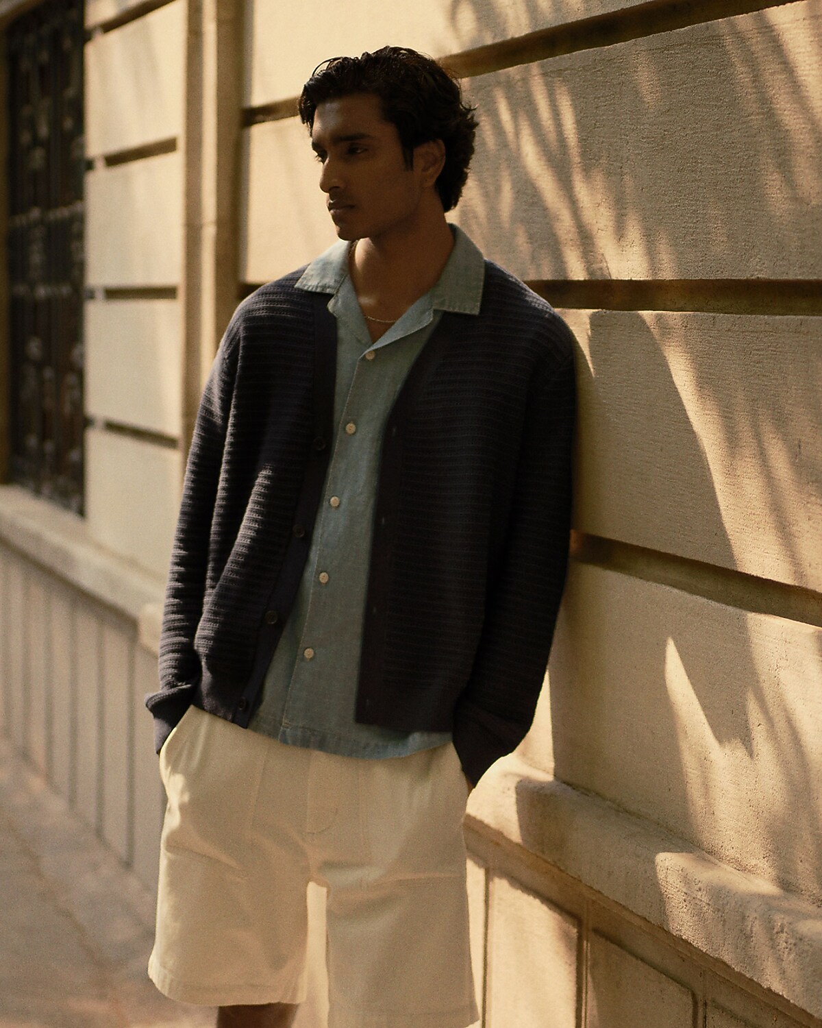 man standing in front of a parachute with classic beige shorts, white top, and a beige shirt