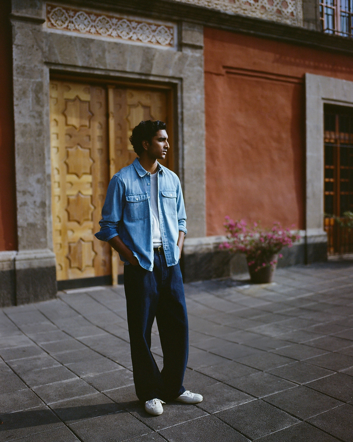 man standing in front of a parachute with classic beige shorts, white top, and a beige shirt